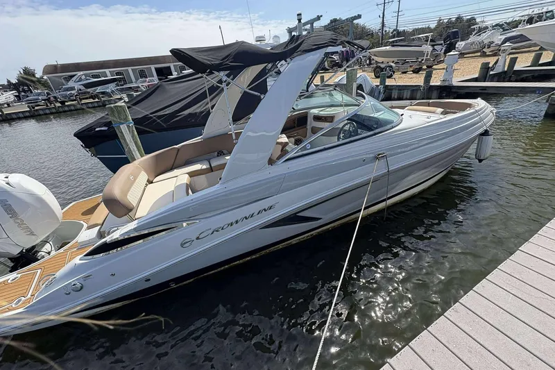 Slide: The Image of 2023 Crownline 280 XSS boat docked at marina, featuring sleek design and spacious seating. - 5