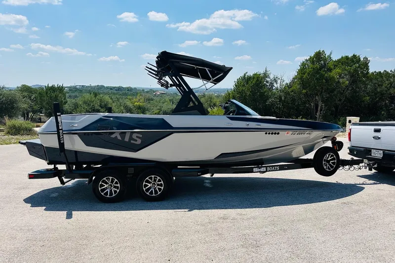 Slide: The Image of 2021 Axis T22 boat on trailer, parked outdoors under a clear blue sky. - 12