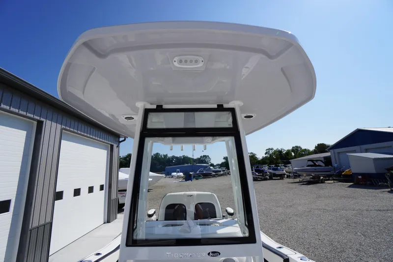 Slide: The Image of 2026 Tidewater 220 LXF boat with T-top, parked outdoors under clear blue sky. - 21