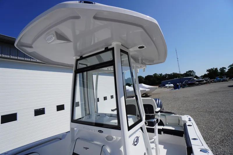 Slide: The Image of 2026 Tidewater 220 LXF boat with T-top and console, parked outdoors. - 37