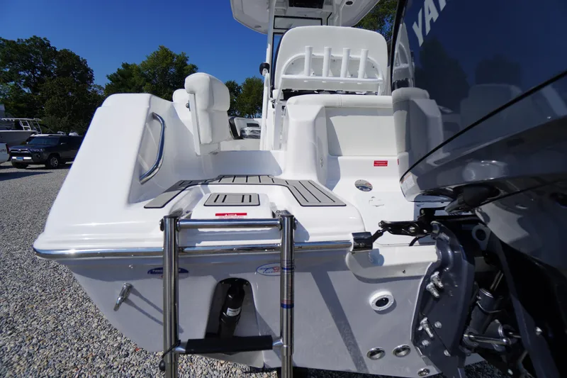 Slide: The Image of 2026 Tidewater 220 LXF boat with swim platform and ladder, parked on gravel. - 58