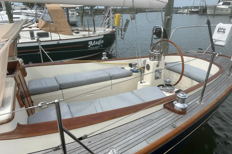 Slide: The Image of 2006 Morris M36 sailboat with wooden deck and cushioned seating in a marina. - 14