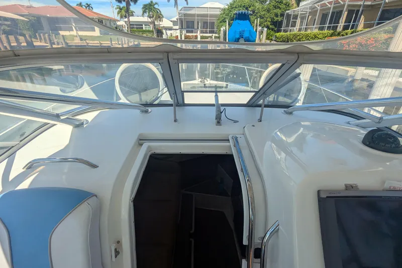 Slide: The Image of 2008 Century 3200 Offshore boat interior with open cabin door, docked near waterfront homes. - 12