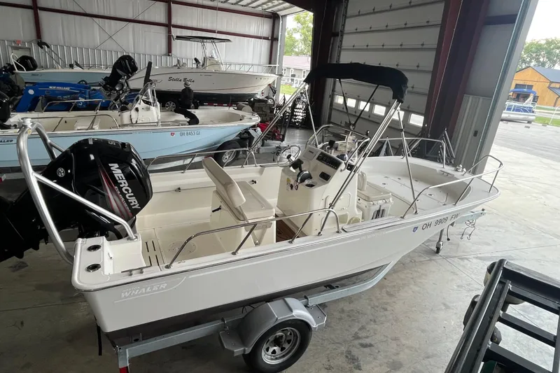 Slide: The Image of 2019 Boston Whaler 170 Montauk boat in storage, featuring a Mercury outboard motor. - 3
