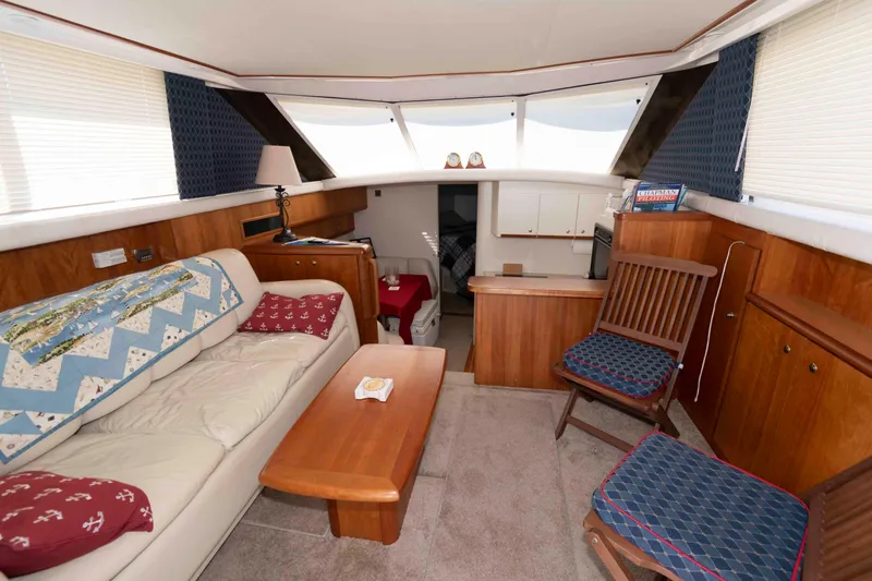 Slide: The Image of Interior of 2000 Silverton 37 Convertible yacht with cozy seating and wooden accents. - 14