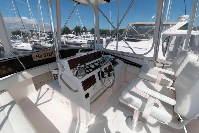 Slide: The Image of 2000 Silverton 37 Convertible yacht helm with dual seats and marina view. - 7