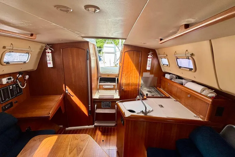 Slide: The Image of Interior of 2002 Hunter 306 sailboat with wood finish and compact kitchen area. - 9