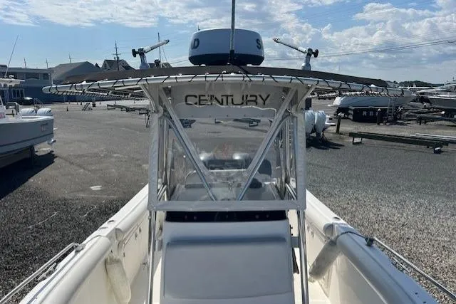 Slide: The Image of 2004 Century 2600 CC boat with T-top, docked in a marina under a clear sky. - 11