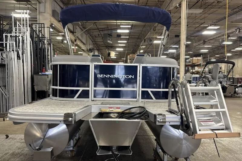 Slide: The Image of 2026 Bennington 23 SSRSF pontoon boat in a workshop with blue cover. - 14