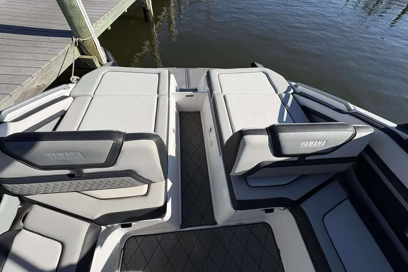Slide: The Image of 2019 Yamaha 275 SE boat interior with cushioned seating near dock. - 10
