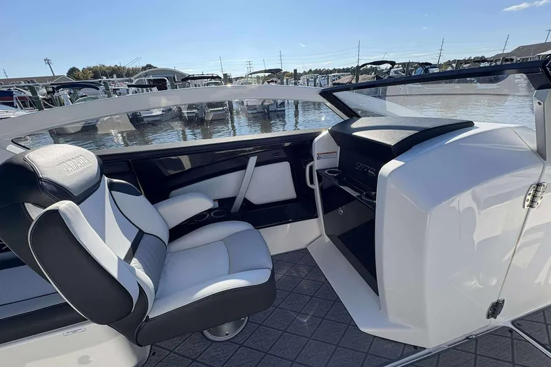 Slide: The Image of 2019 Yamaha 275 SE boat interior with sleek seating and dashboard, docked at marina. - 20