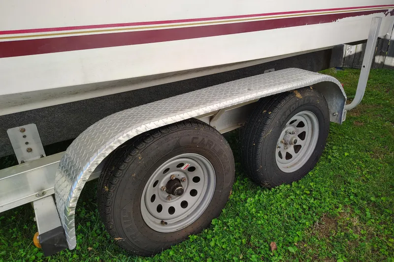 Slide: The Image of Trailer wheels of a 1995 Sea Ray 250 Sundancer boat on grass. - 10