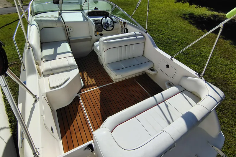 Slide: The Image of 1995 Sea Ray 250 Sundancer boat interior with white seating and wooden flooring. - 11