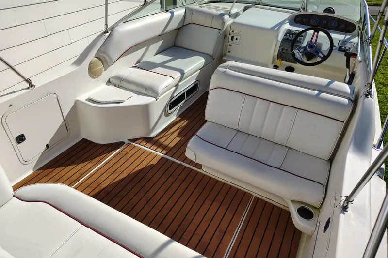 Slide: The Image of 1995 Sea Ray 250 Sundancer boat interior with white seating and wooden flooring. - 12