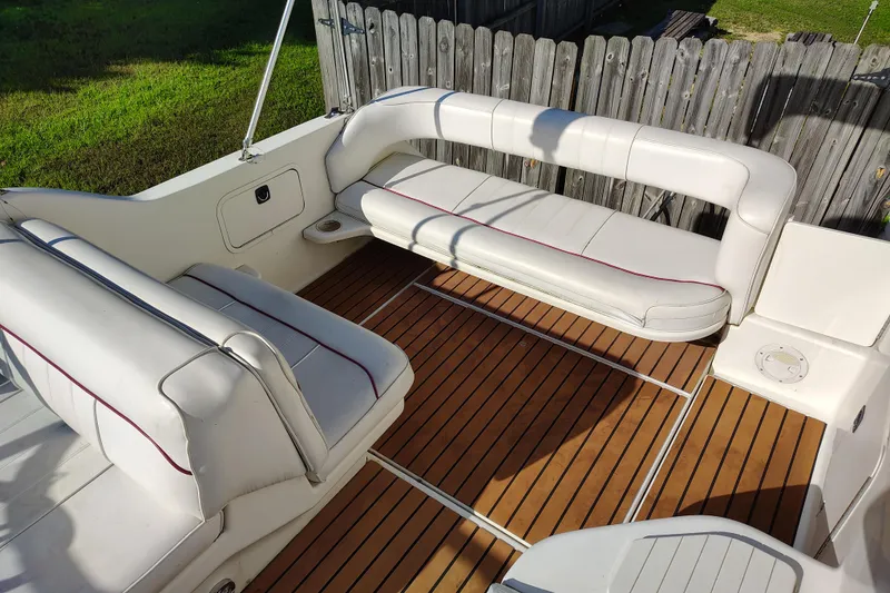 Slide: The Image of 1995 Sea Ray 250 Sundancer boat interior with white seating and wooden deck. - 13