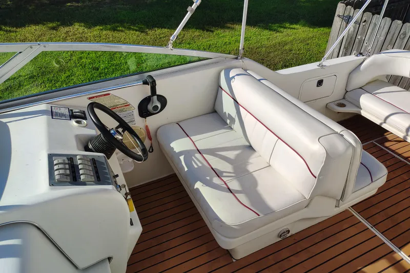 Slide: The Image of 1995 Sea Ray 250 Sundancer boat interior with white seating and wooden deck. - 14