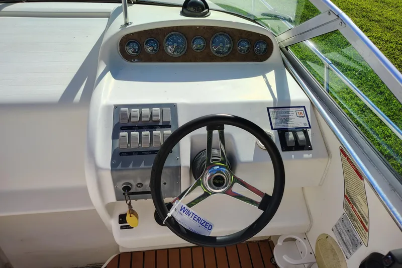 Slide: The Image of 1995 Sea Ray 250 Sundancer helm with steering wheel, gauges, and control switches. - 16