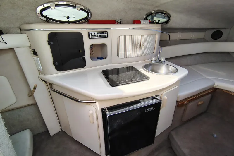 Slide: The Image of 1995 Sea Ray 250 Sundancer cabin interior with kitchenette, sink, and mini fridge. - 18