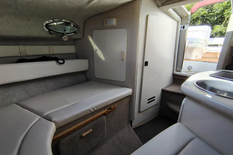 Slide: The Image of Interior of 1995 Sea Ray 250 Sundancer boat, featuring seating and compact kitchenette. - 24