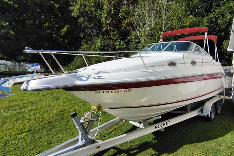Slide: The Image of 1995 Sea Ray 250 Sundancer boat on trailer, parked on grass with trees in background. - 3