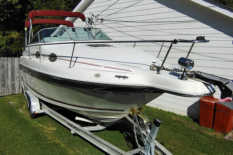 Slide: The Image of 1995 Sea Ray 250 Sundancer boat on trailer, parked beside a white building. - 4