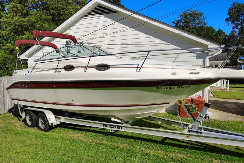 Slide: The Image of 1995 Sea Ray 250 Sundancer boat on trailer, parked beside a white house. - 5