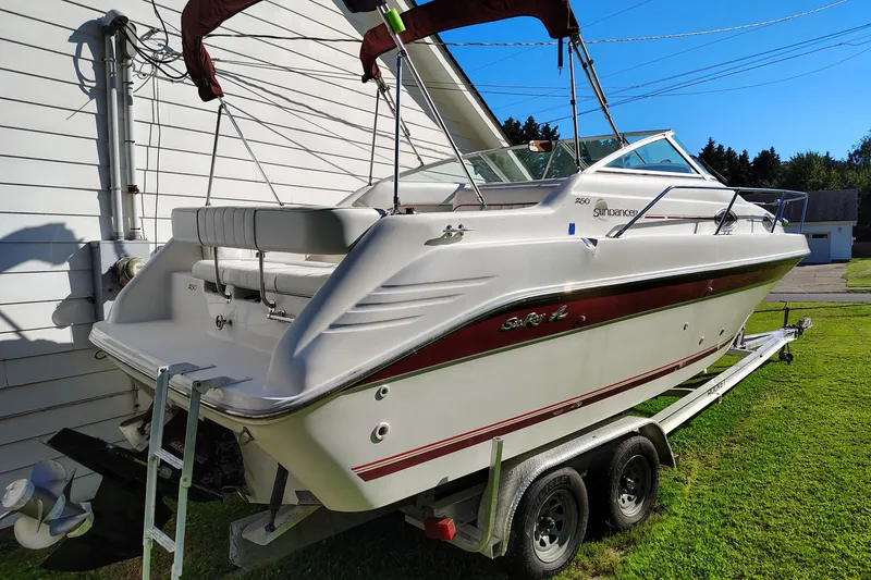 Slide: The Image of 1995 Sea Ray 250 Sundancer boat on trailer, parked beside a white building. - 6