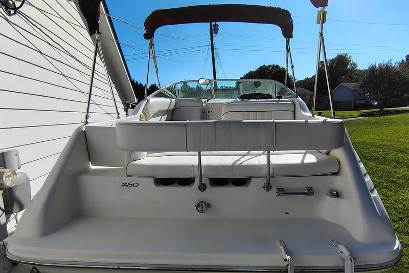 Slide: The Image of 1995 Sea Ray 250 Sundancer boat with white seating and canopy, parked outdoors. - 7