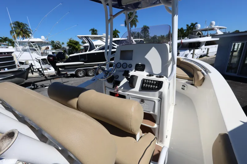 Slide: The Image of 2019 NauticStar 2302 Legacy boat interior with helm, beige seating, and control panel. - 10