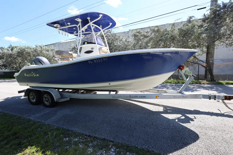 Slide: The Image of 2019 NauticStar 2302 Legacy boat on trailer, parked outdoors. - 7