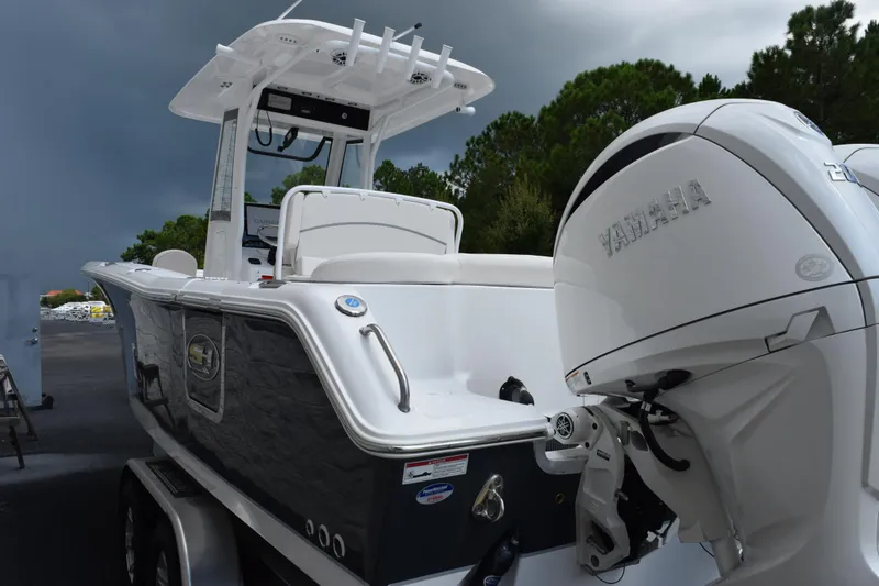 Slide: The Image of 2026 Sea Hunt Ultra 265 SE boat with Yamaha engine, parked outdoors under cloudy sky. - 5
