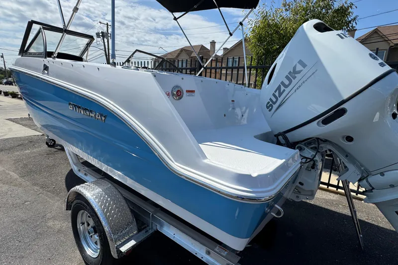 Slide: The Image of 2026 Stingray 172 SC boat with Suzuki outboard motor, parked on a trailer. - 2