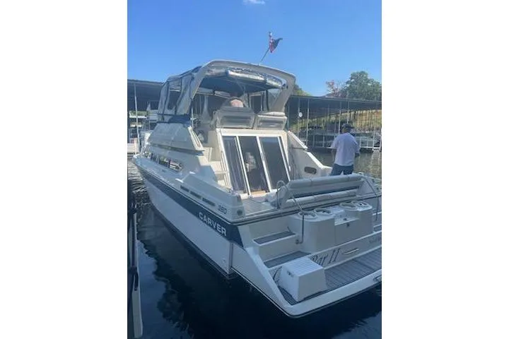 Slide: The Image of 1990 Carver 34 - 38 yacht docked, featuring spacious deck and cabin area. - 7