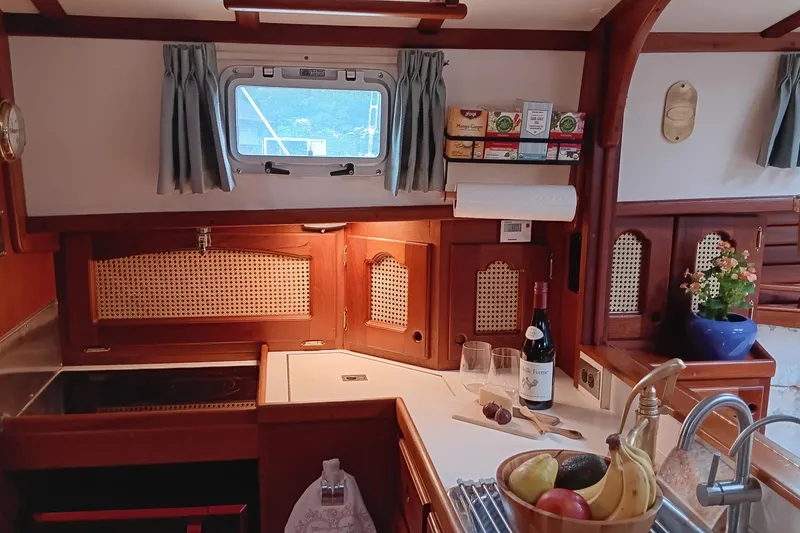 Slide: The Image of Cozy 1991 Gozzard 31 yacht kitchen with wooden cabinetry, fruit bowl, and wine bottle. - 15