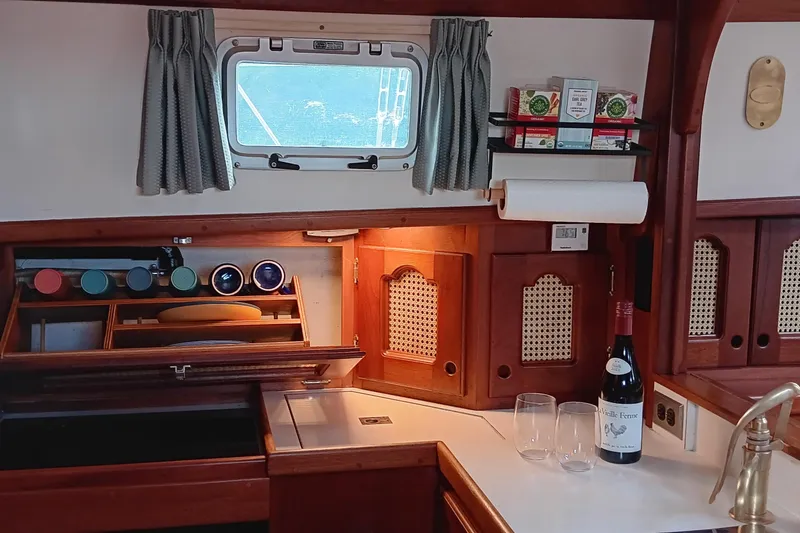 Slide: The Image of Cozy 1991 Gozzard 31 yacht interior with wooden cabinetry and kitchen essentials. - 16