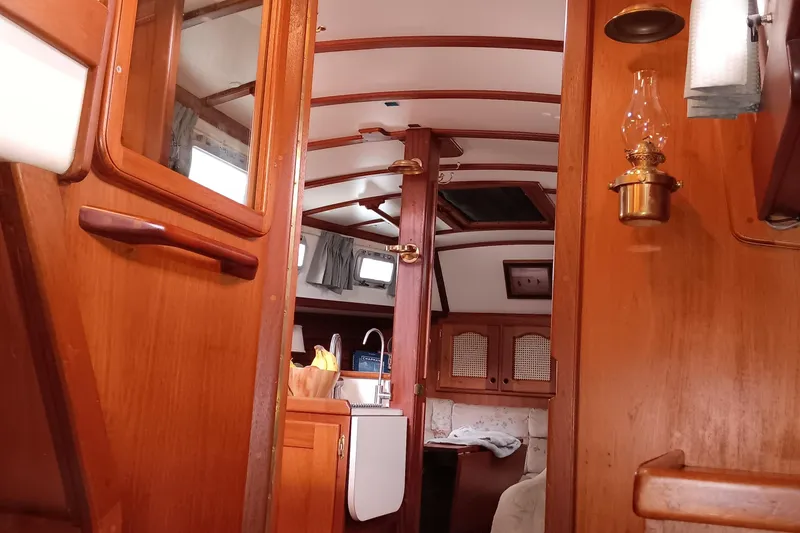Slide: The Image of Interior of a 1991 Gozzard 31 sailboat, featuring wooden cabinetry and cozy seating. - 28
