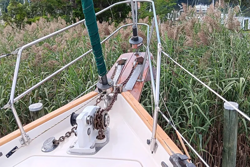 Slide: The Image of Bow of 1991 Gozzard 31 sailboat with anchor chain, surrounded by tall grass. - 3