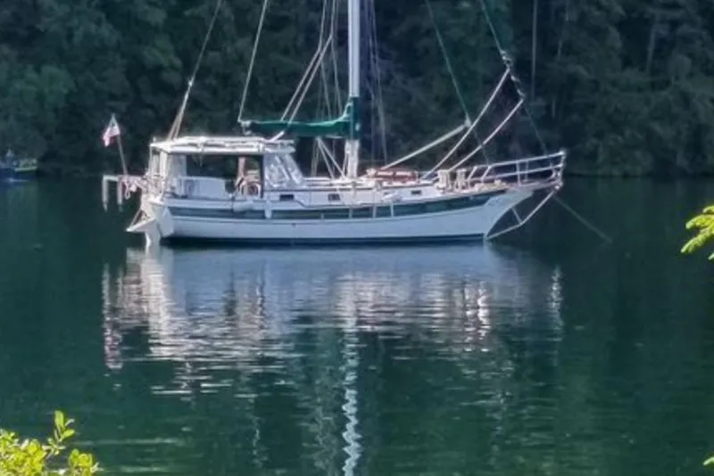Slide: The Image of Sailboat Gozzard 31 (1991) anchored on a serene lake surrounded by lush forest. - 45