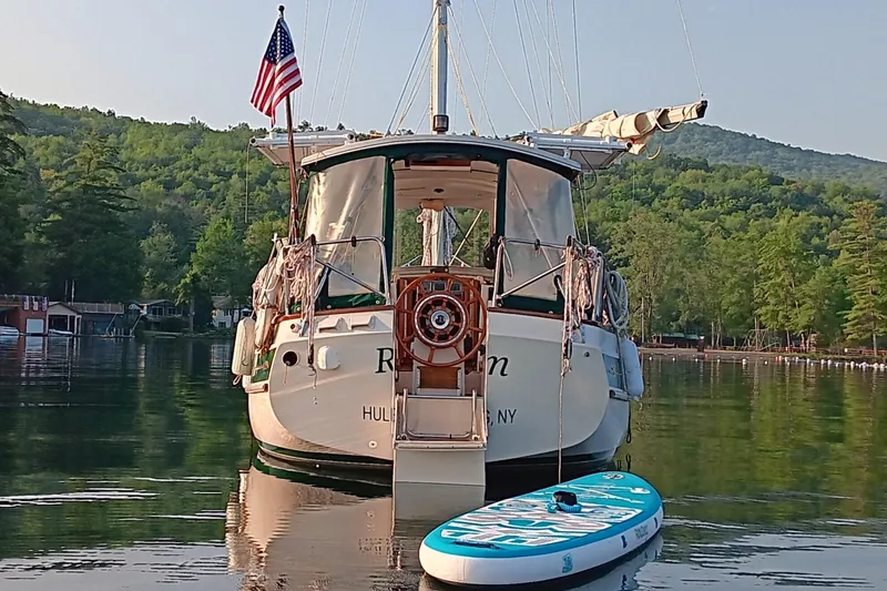 Slide: The Image of Sailboat Gozzard 31 (1991) with paddleboard on calm lake, surrounded by lush greenery. - 46