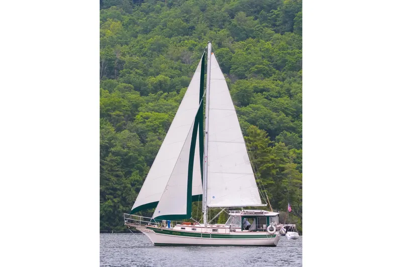 Slide: The Image of Sailboat Gozzard 31 (1991) on calm water with lush green forest backdrop. - 48