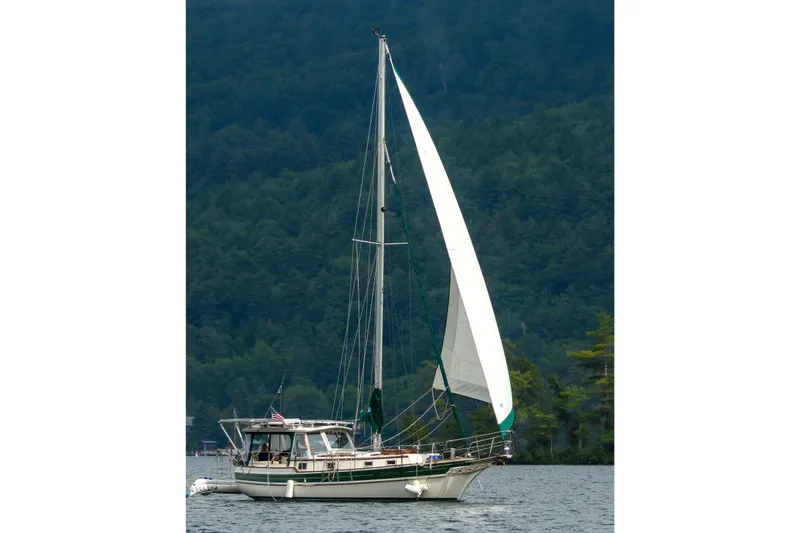 Slide: The Image of Sailing yacht Gozzard 31 from 1991 on a serene lake with forested backdrop. - 49