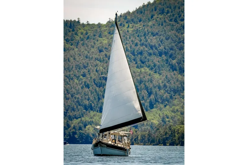 Slide: The Image of Sailboat Gozzard 31 (1991) gliding on water with forested hills in background. - 50