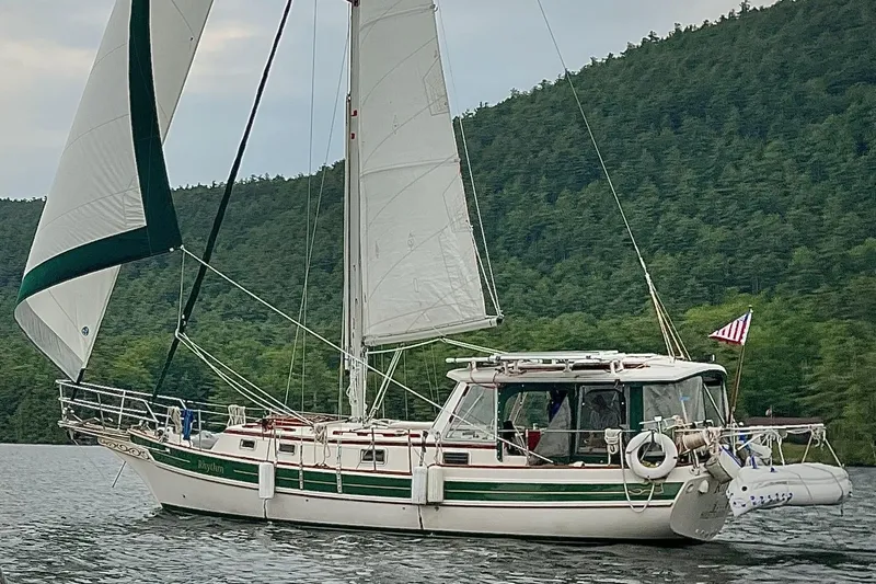 Slide: The Image of Sailing yacht Gozzard 31 from 1991 on a serene lake with forested hills. - 52