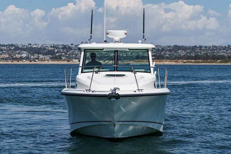 Slide: The Image of 2018 Boston Whaler 315 Conquest boat cruising on open water, cityscape in background. - 2