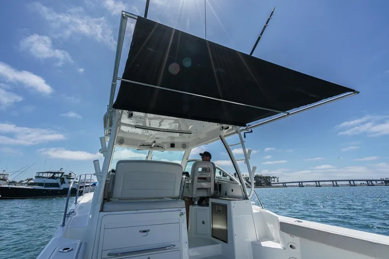 Slide: The Image of 2018 Boston Whaler 315 Conquest boat on water, featuring a sunshade and clear blue sky. - 20