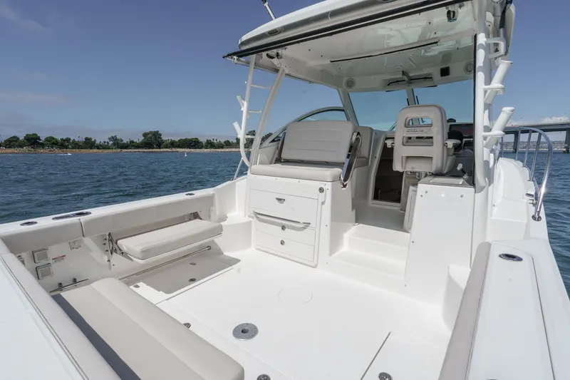 Slide: The Image of 2018 Boston Whaler 315 Conquest boat interior with seating and storage, on calm water. - 21