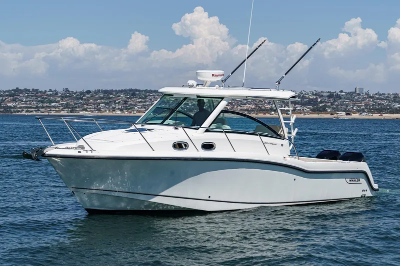 Slide: The Image of 2018 Boston Whaler 315 Conquest boat on calm water with cityscape background. - 3