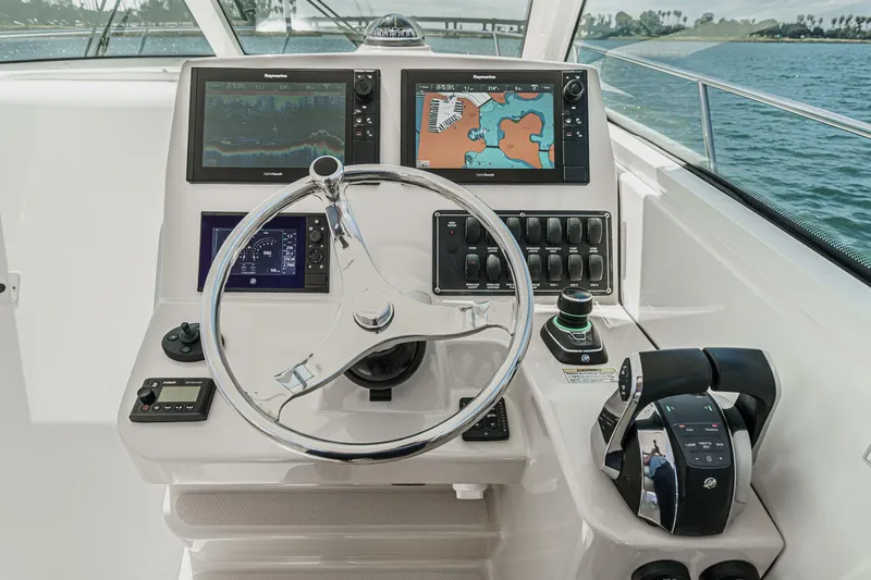 Slide: The Image of 2018 Boston Whaler 315 Conquest helm with navigation screens and controls on open water. - 30