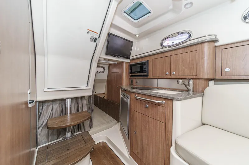 Slide: The Image of 2018 Boston Whaler 315 Conquest cabin interior with kitchenette and seating area. - 35