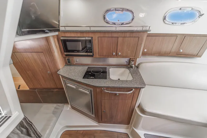 Slide: The Image of 2018 Boston Whaler 315 Conquest interior kitchen with microwave, sink, and wooden cabinetry. - 37